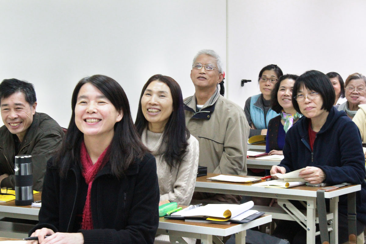 廣論研討班教室內，多位學員並肩而坐、笑容滿面地進行課程互動，展現溫馨的學習氣氛與友誼